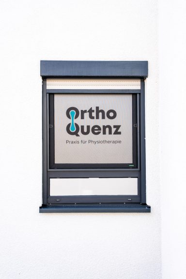 Schild von OrthoQuenz mit moderner Schrift auf hellen Hintergrund.