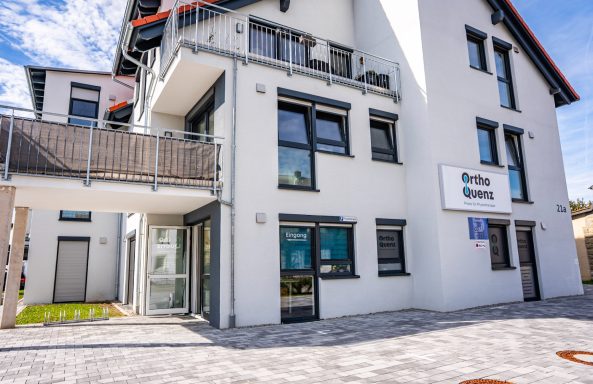 Moderner, heller Gebäudekomplex mit Balkon und großen Fenstern.